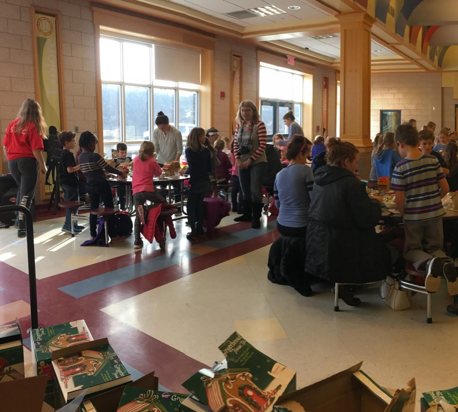 Hingham High Student Council members mingle with elementary school students, walking around and sitting down to help them.