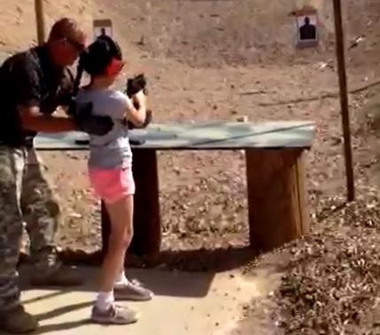 Shooting instructor Charles Vacca stands next to a 9-year-old girl at the Last Stop shooting range in White Hills, Arizona near the Nevada border, on August 25, 2014, in this still image taken from video courtesy of the Mohave County Sheriffs Office. 