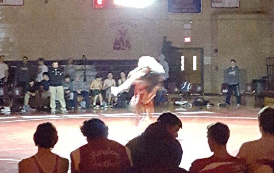 A Hingham wrestler throws Duxbury opponent on the ground