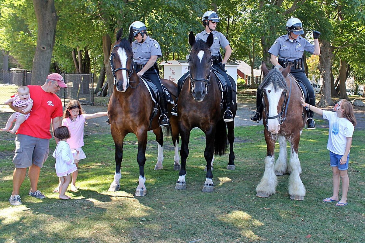 To the left, Recreational director Mike Bernard and his three little girls standing next to the Massachusetts State Police Horse Force. 