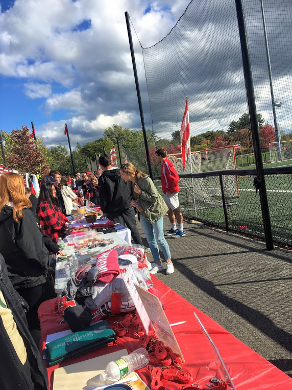 Hingham fans shop at activity tables on the outside of the turf field during the girls soccer game of Homecoming.