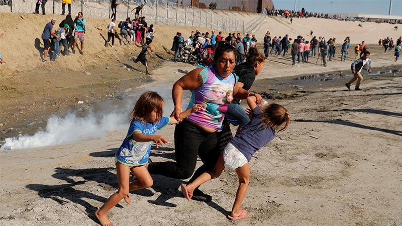 A family, including a mother and two little girls in diapers, run from the tear gas released by the U.S. Border Patrol at the U.S.-Mexico border.