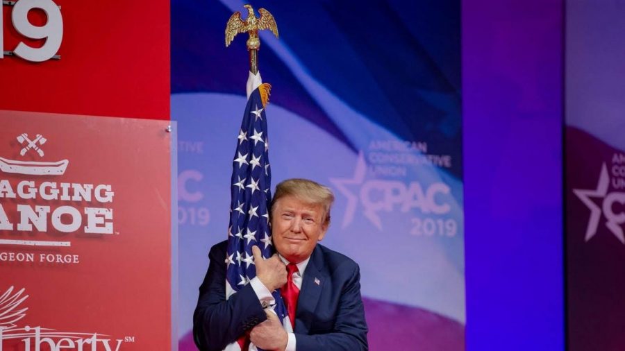 Trump hugging the US flag at the CPAC (Photo by Tasos Katopodis)