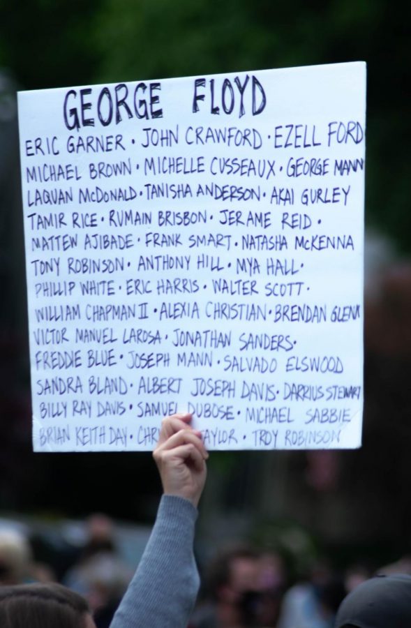 A man holds up a sign that lists all the black victims of police brutality.