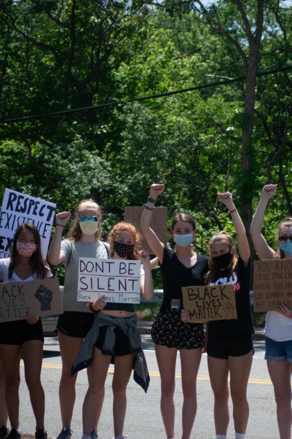 A group of Hingham girls faces the camera, holding up the Black Lives Matter fist.