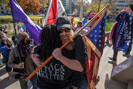Despite having political differences, Trump Supporter Kevin Skinner and Black Lives Matter member Marvin F embrace at Michigans State Capitol.