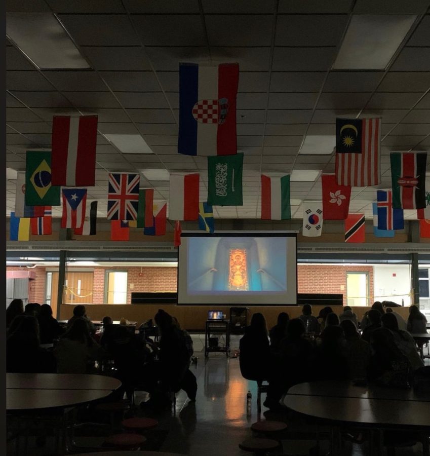 On+Wednesday+night%2C+students+gathered+in+the+cafeteria+to+watch+the+new+Disney+movie%2C+Encanto.+Flags+representing+students+in+the+HHS+community+hang+above.