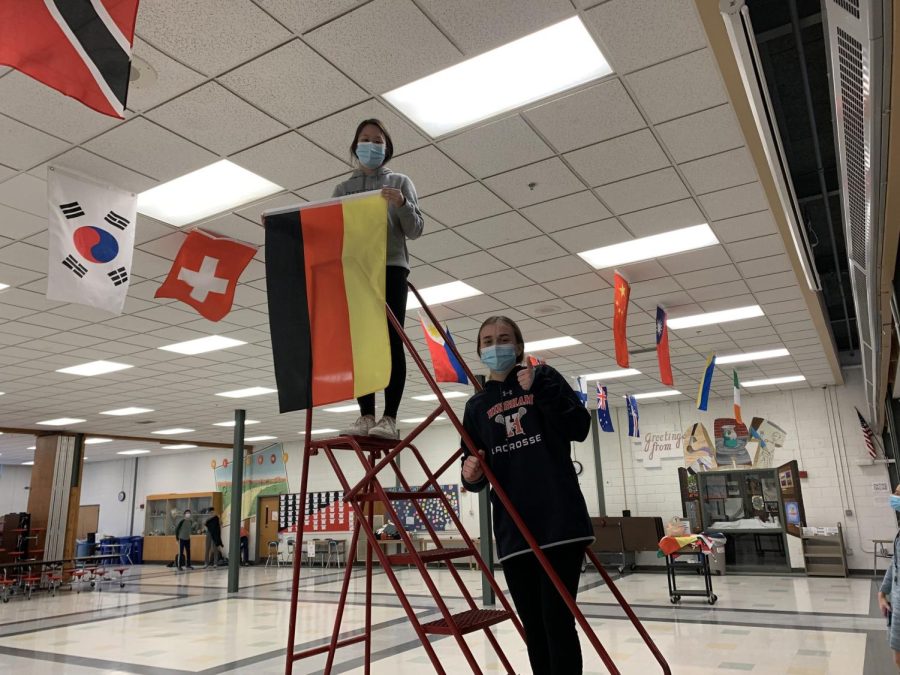 Senior Mimi Jiang-Yu (left) and Junior Lily Ehler (right) put up flags in the cafeteria.