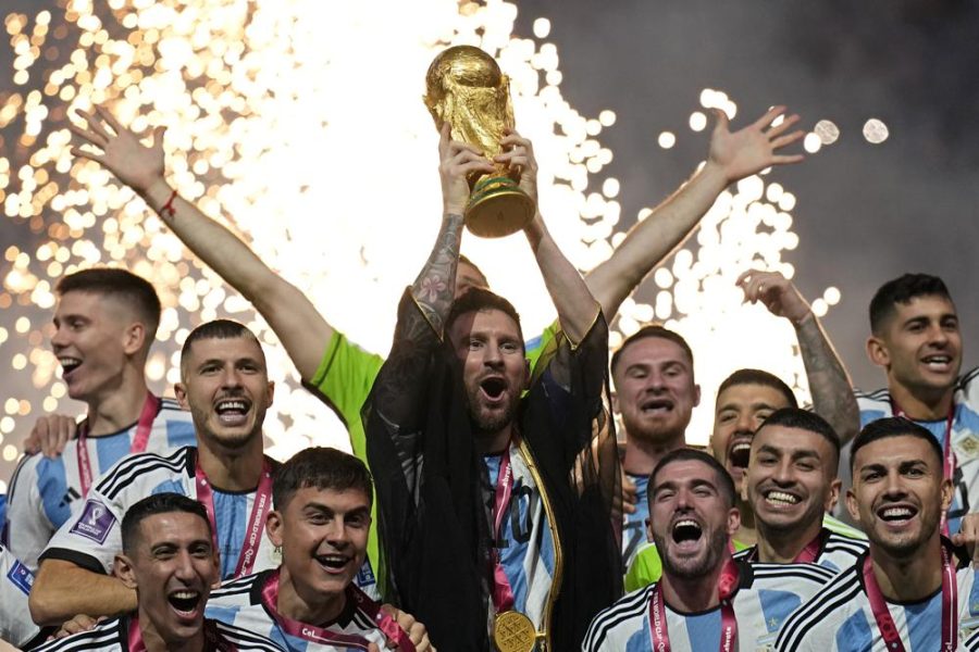 Lionel Messi holds up the winning trophy in celebration alongside the Argentina team. 