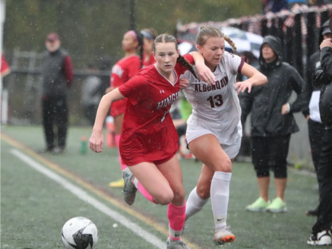 Hingham’s Kiki McGourty wards off an Algonquin forward as she outruns her to the ball. 
By: Joshua Ross Photography 