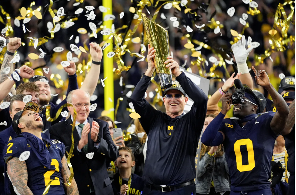 Michigan+head+coach+Jim+Harbaugh+raising+the+championship+trophy+after+defeating+Washington+in+the+National+Championship+Monday+night+%28Eric+Gay%29