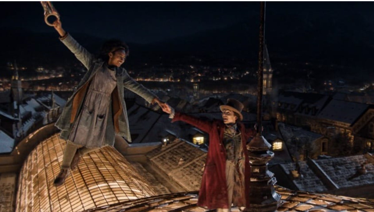 Willy (Timothy Chalamet) and Noodle (Calah Lane) skip across rooftops aided by a bundle of balloons (Photo Credit: Warner Bros. Pictures all rights reserved).