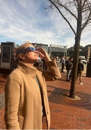 Hingham resident Hillary Flynn uses her eclipse glasses to witness the event on April 8th in Boston. 
