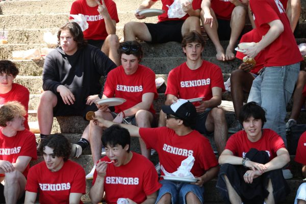 A group of senior boys sit on steps eating lunch during HHS’ annual field day. 
