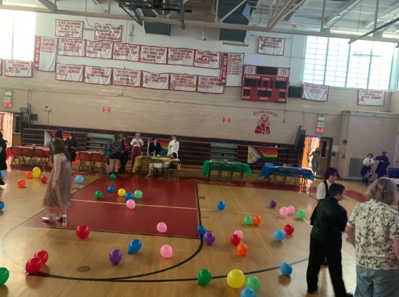 The queer prom before sunset, with a few students and some balloons scattered on the floor.
