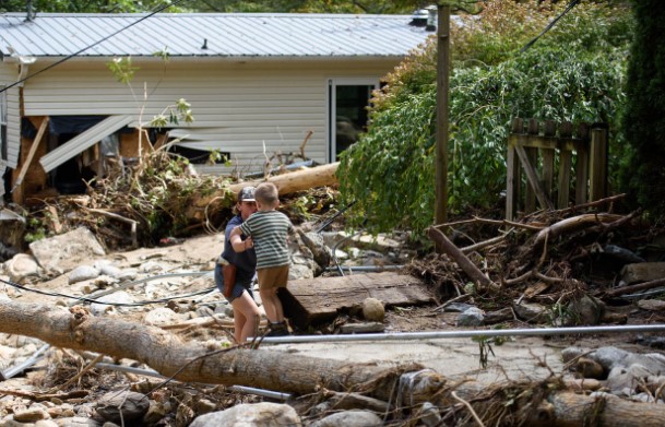 Leo Grindstaff, 12, left, helps his brother Gabe, 4, while they journey to their grandparent's house to salvage items on Sept. 30, 2024, in Old Fort, North Carolina. 
