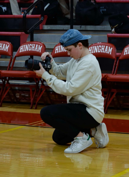 Ned Wittmann takes photos of a basketball game at Hingham High School’s gymnasium.
