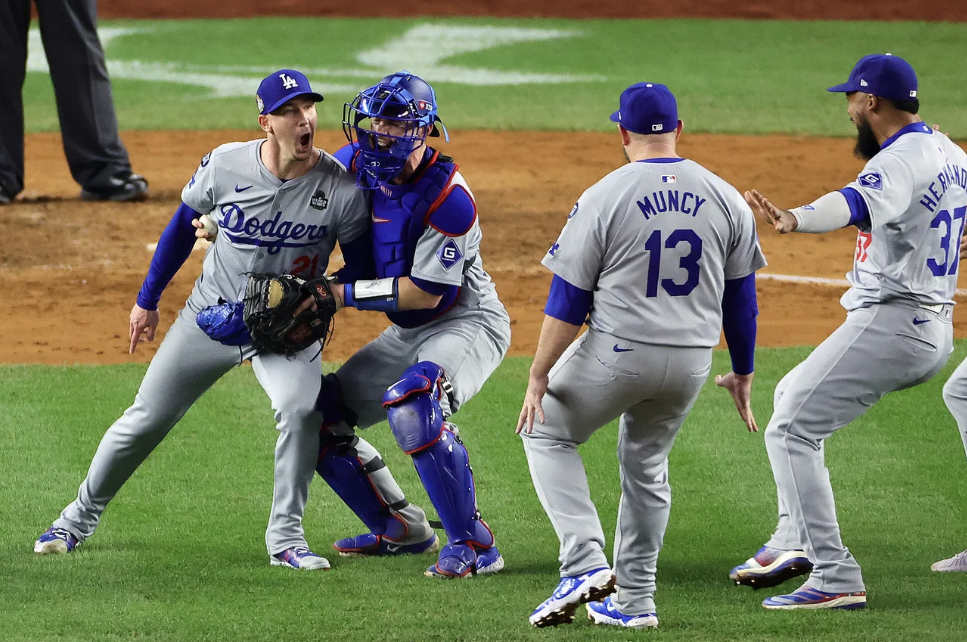 Dodgers players rush to Walker Buehler after winning the 2024 World Series vs the New York Yankees.