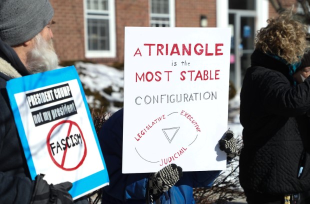 Local residents showing off their creative protest signs in downtown Hingham.  (Photo by Josh Ross)

