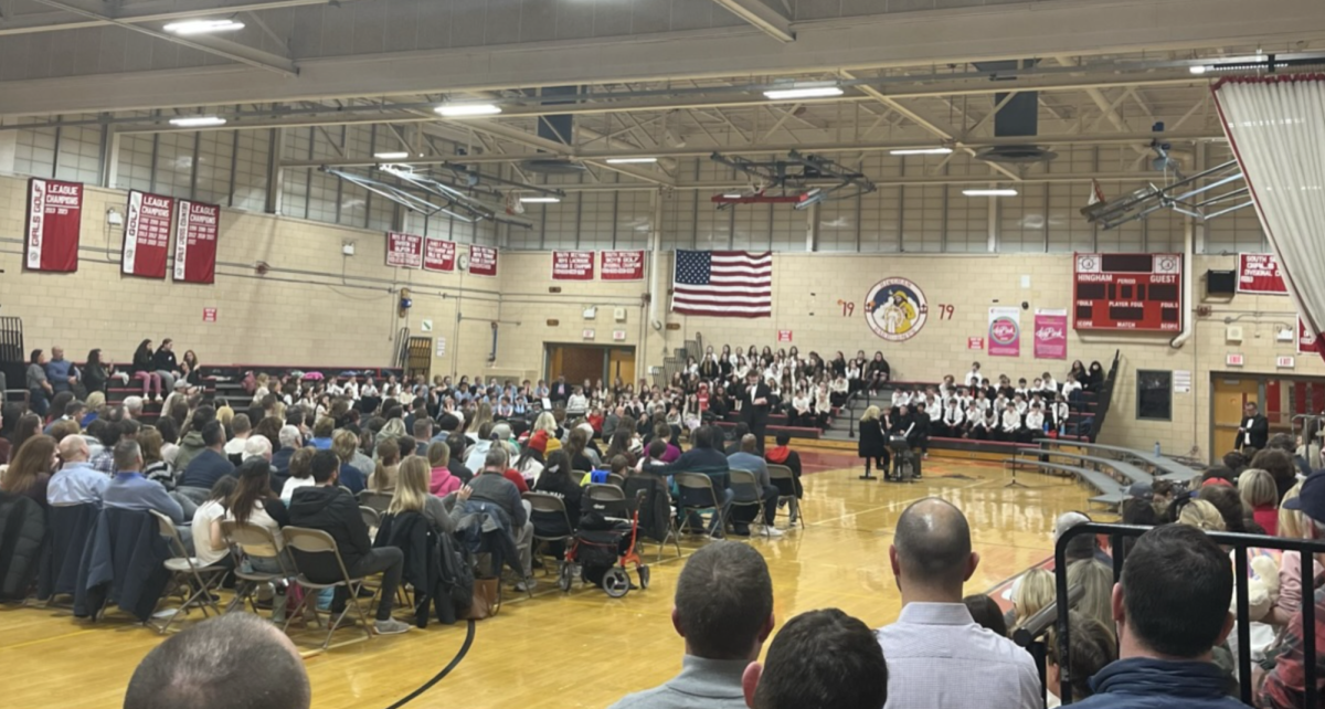 HHS senior chorus member Nick Roche speaks about his experience in the Hingham chorus program in the packed gym at the All Town chorus concert on Monday, 3/3/25.