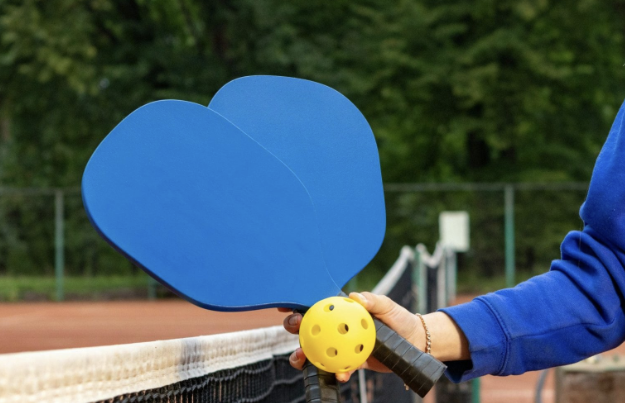 Two pickleball rackets and a ball being held and waiting to play.