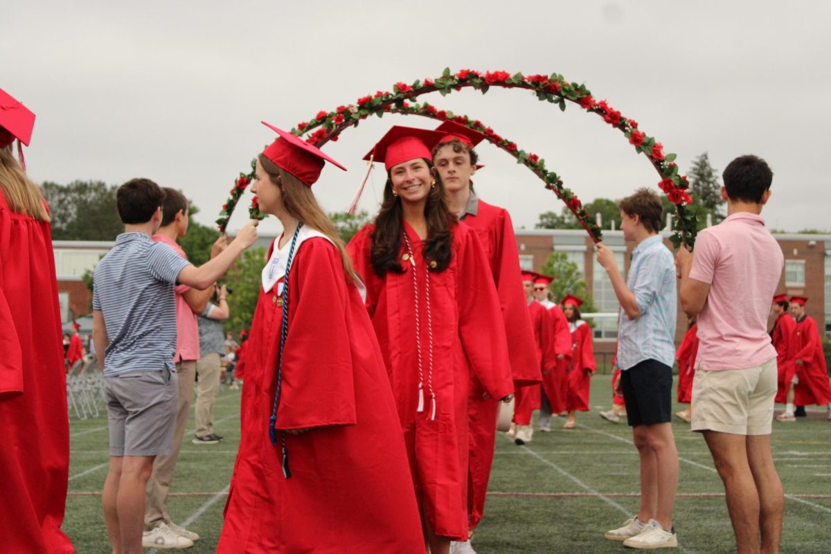 The seniors are ushered into their graduation ceremony under beautiful rose arches, held up by the younger siblings of the graduates.  
