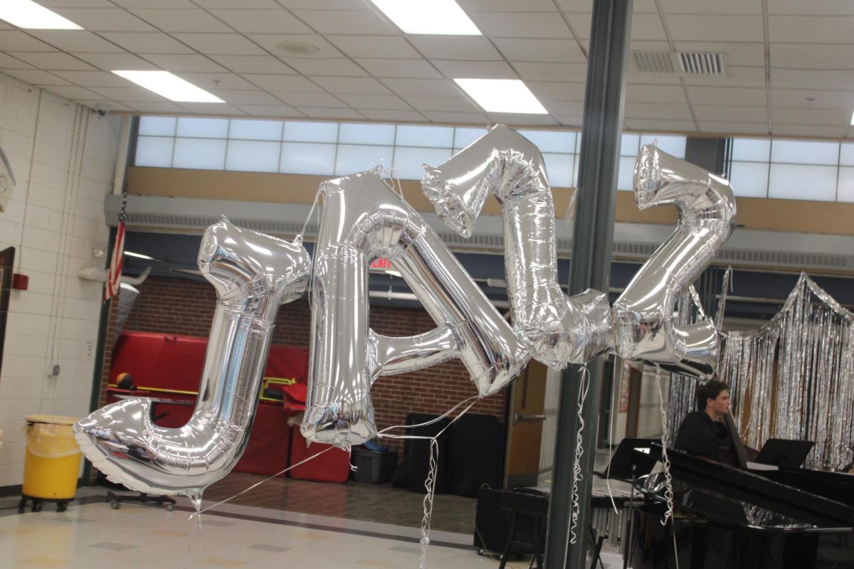Balloon letters spelling out "JAZZ" float above a crowded cafeteria.