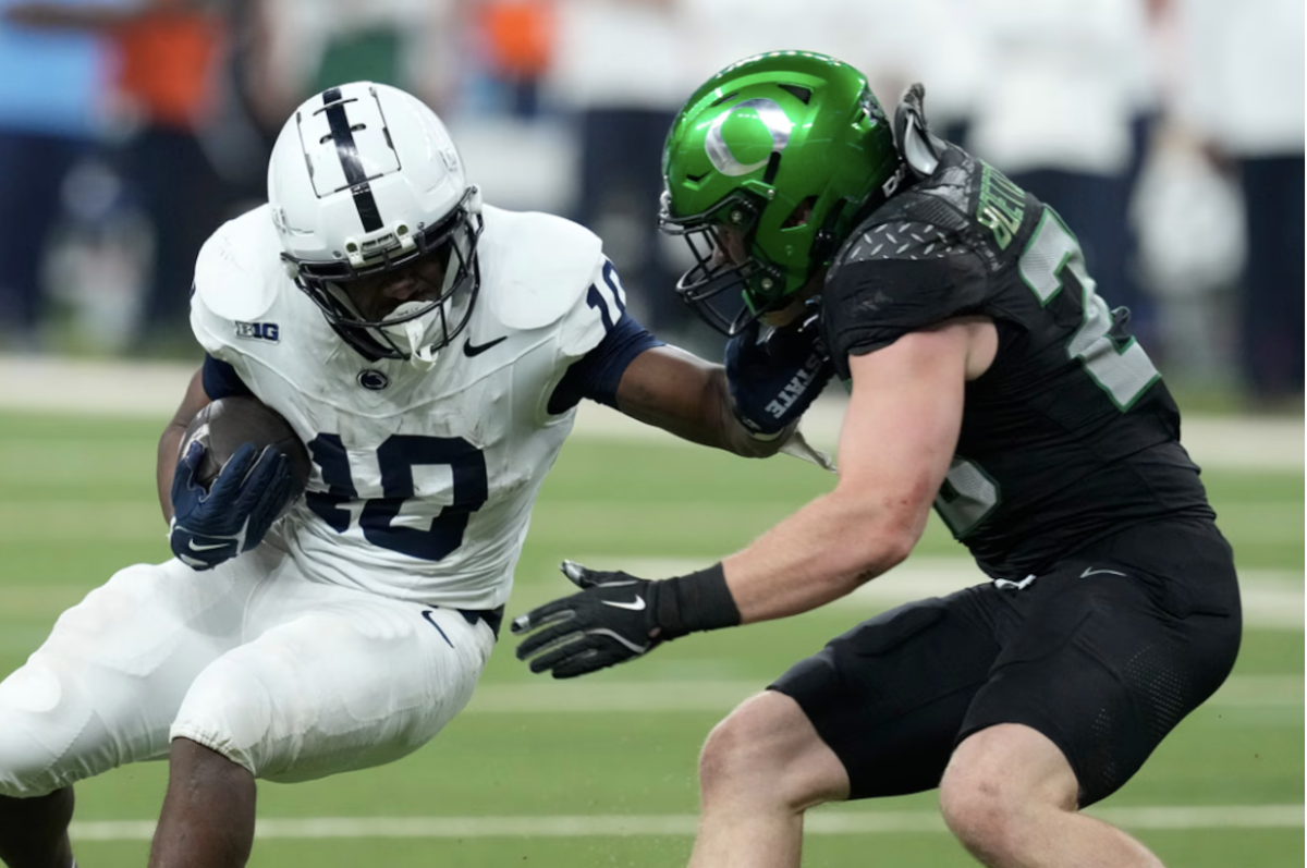 Penn State running back Nicholas Singleton (10) stiff arms Oregon linebacker Bryce Bottecher (28) prior to getting tackled in the 2024 Big Ten Championship.