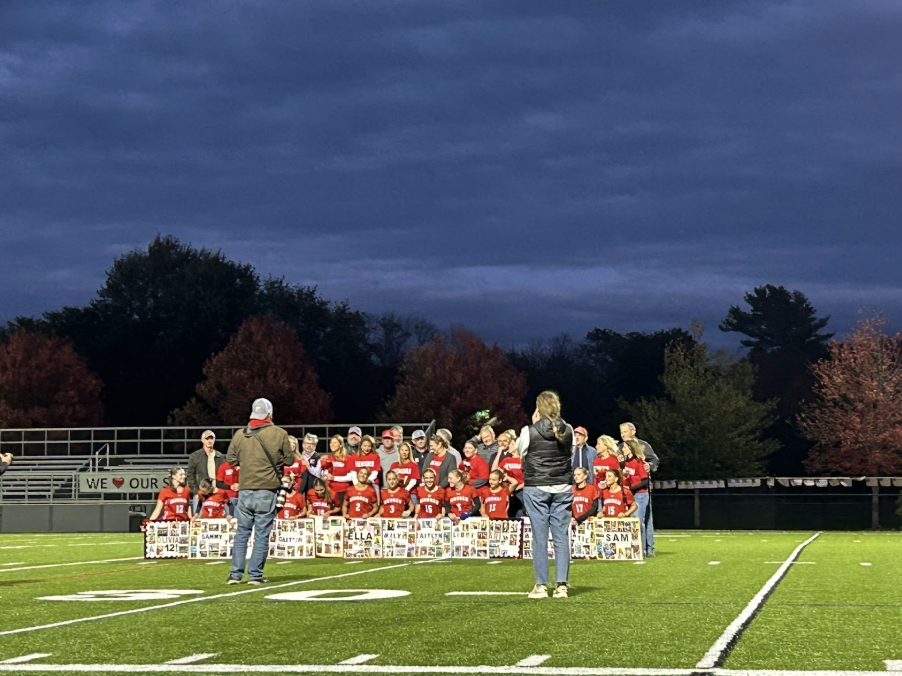 The 13 varsity seniors and their parents line up for a photo taken by Josh Ross, accompanied by JV Coach Baggott.