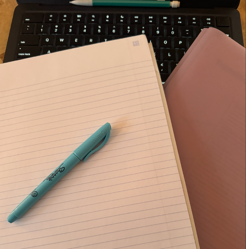 A student lays out their computer, folder, notebook, pencil, and highlighter of choice to study for midyear exams.