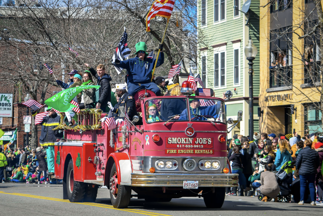 A fire engine rolls through the Boston St. Patrick's Day parade while families and friends cheer on the sidelines.