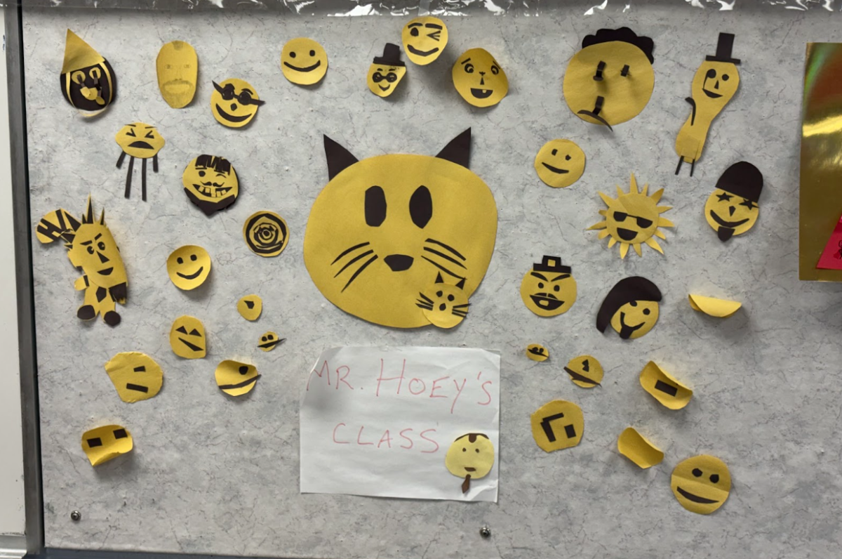 The smiley faces made on the first day of the production line activity are displayed on the wall of Room 171.
