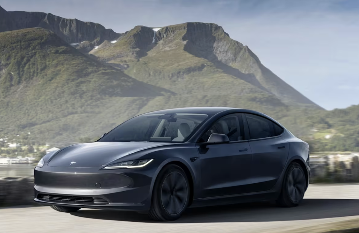 Tesla Model 3 drives near a mountain.