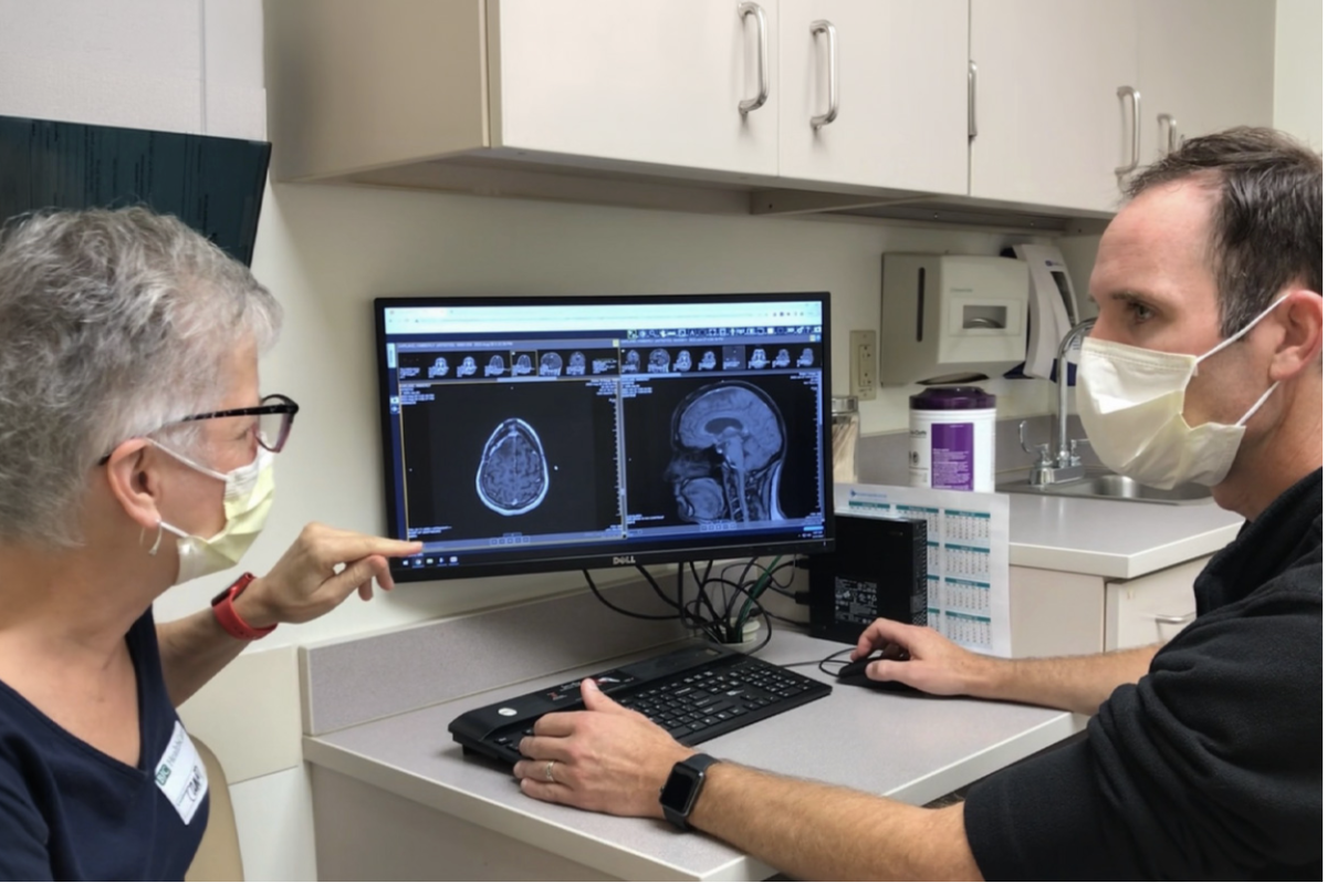 Kim Garland (left) reviews brain scan with study’s primary investigator, Tanner Johanns (right). 
