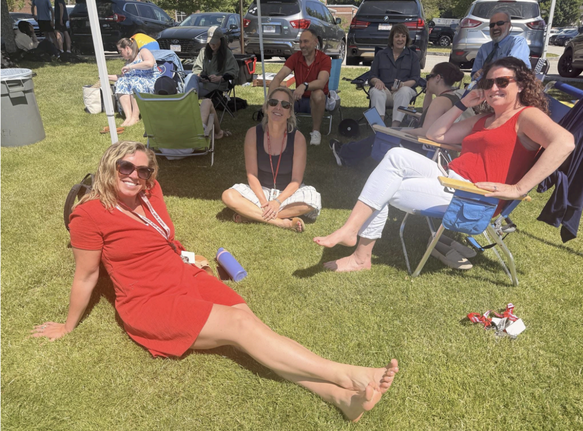 Mrs. Hart (red dress) and her coworkers enjoy sitting under the sun.